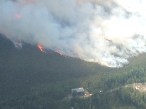 A helicopter, lower right, conducts bucket operations on the Moose Creek Fire that escaped from the Northway dump on Friday afternoon. The fire was estimated at 278 acres on Saturday.