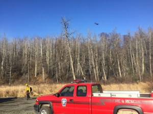 A helicopter with a water bucket flies over the Moose Creek Fire about 5 miles south of Sutton on Saturday afternoon near the area being used as a staging area for firefighters. Photo by Sarah Saarloos/Alaska Division of Forestry