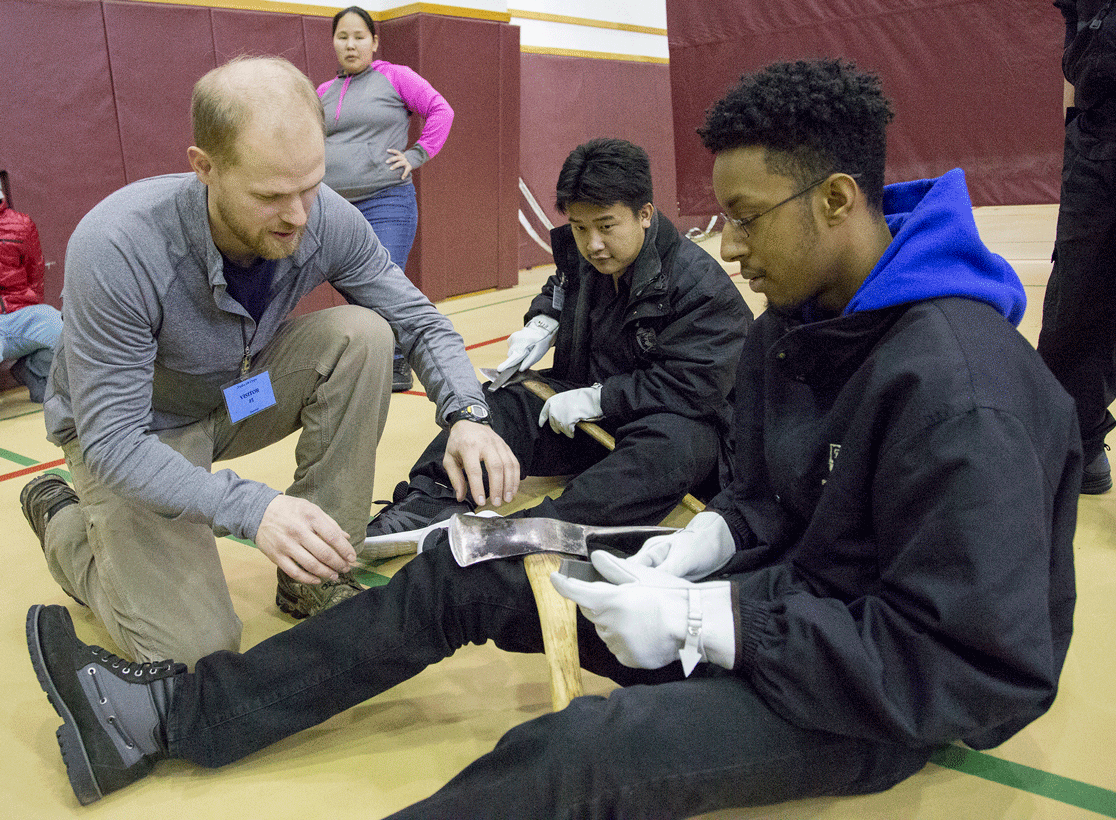 Instructor Ben Ferguson, on left, helps Alaska Job Corps student Esai Montes as he and fellow student Ying Yang learn to sharpen pulaskis during a basic wildland firefighting class on Feb. 8, 2017