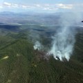 Sixteen smokejumpers and two Fire Boss aircraft are working on the 25-acre Hughes Mountain Fire burning in steep terrain four miles west of Hughes (pictured in the distance)Photo by John Lyons, BLM AFS