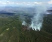 Sixteen smokejumpers and two Fire Boss aircraft are working on the 25-acre Hughes Mountain Fire burning in steep terrain four miles west of Hughes (pictured in the distance)Photo by John Lyons, BLM AFS