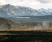 Photo of a firefighter using a drip torch to light grass on fire to burn off dead grass on military lands in the Donnelly Training Area in April 2016.