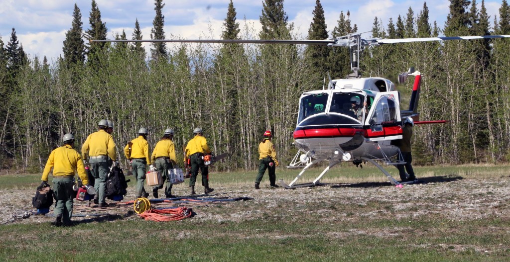 Photo of Pioneer Peak Interagency Hotshot Crew firefighters walking to a helicopter that will shuttle to the fireline on May 15, 2019.