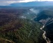 Aerial view of the Chetaslina Fire (#606) showing burned area, green vegetation, minimal smoke, and rain in the distance.