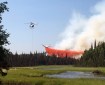 A helicopter dips a bucket of water out of pond while an air tanker drops a load of retardant on the Malaspina Fire on Sunday, July 7, 2019. Photo by Ed Soto/Alaska Division of Forestry