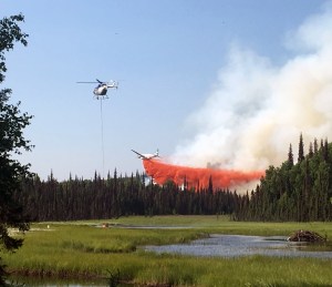 A helicopter dips a bucket of water out of pond while an air tanker drops a load of retardant on the Malaspina Fire on Sunday, July 7, 2019. Photo by Ed Soto/Alaska Division of Forestry