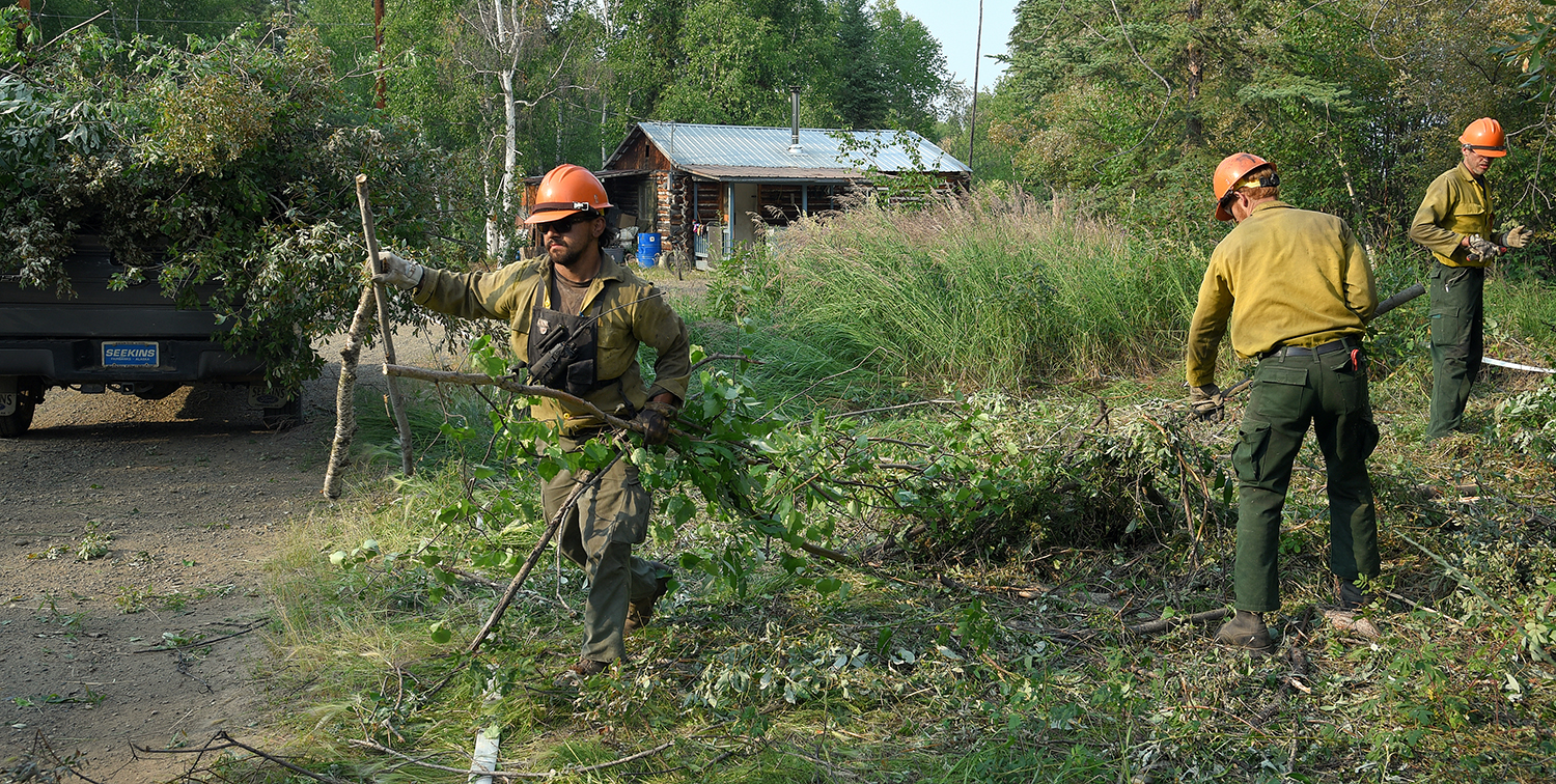Photo of Members of the North Star Type 2 hand crew pick up brush piles in the village of Chalkyitsik, Alaska, on Saturday, July 13, 2019. Firefighters have completed their structure protection setup in the community of 57 residents. The Frozen Calf Fire (#367) and the Bearnose Hill Fire (#407) continue to grow toward the village. Sam Harrel/Alaska Interagency Incident Management Team