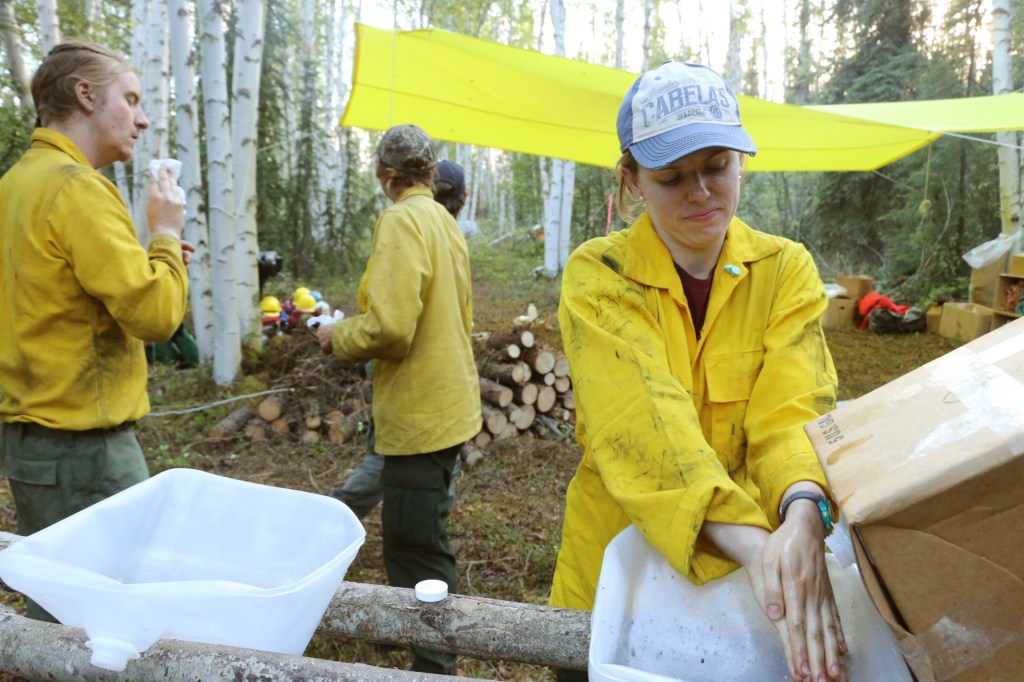 Firefighter Candice Norman washes her hands in a makeshift wash basin made out of an empty cubie on the Zitziana River Fire in June of 2018.