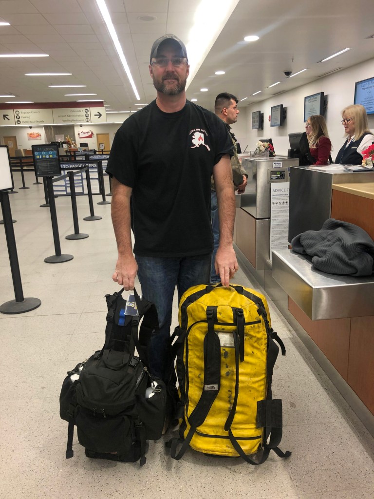 Man standing with his firefighting gear at airport.