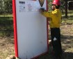 A firefighter stapling updated information on a board.