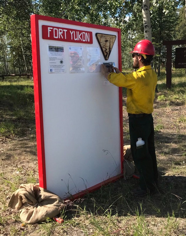 A firefighter stapling updated information on a board.