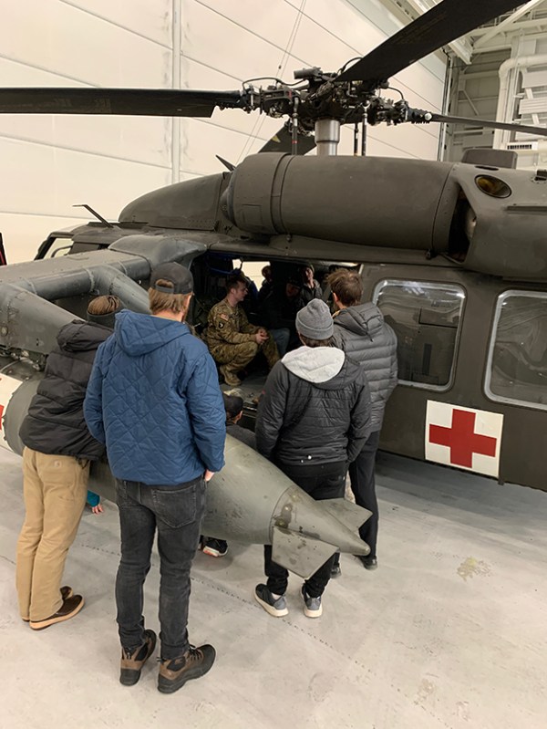 People peering into an Army Blackhawk helicopter.
