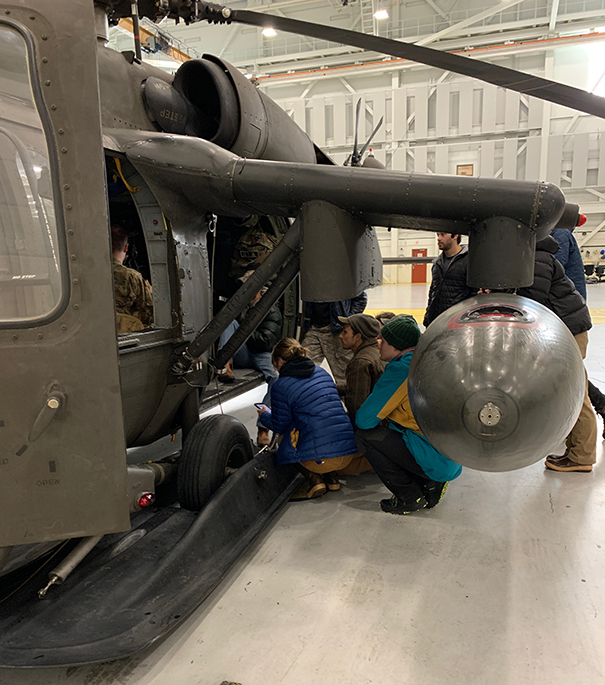 People peering into an Army Blackhawk helicopter.