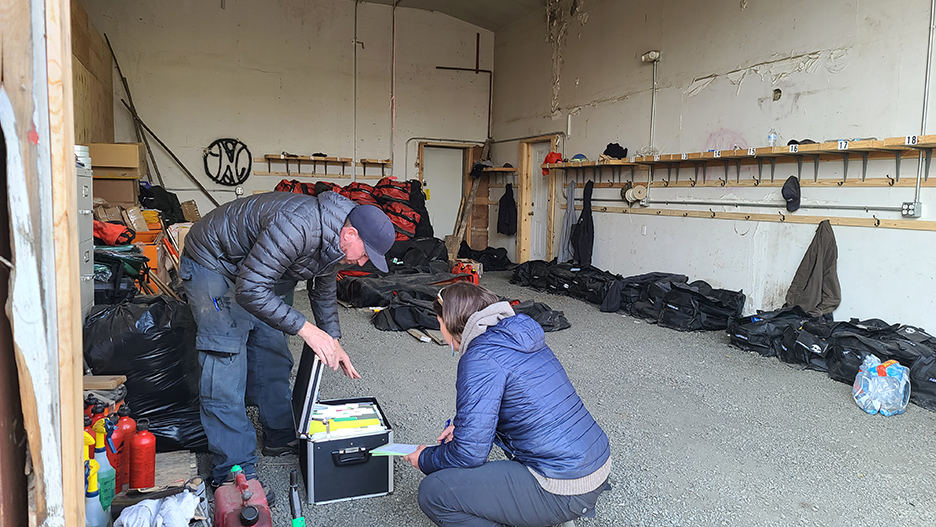 A man bent over a box of files while talking to a woman kneeling down in front of the file box.