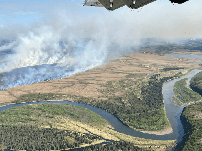 Aerial photo of smoke billowing up from a tundra fire near a river.