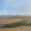 Photo of a flat tundra landscape with wispy smoke columns.