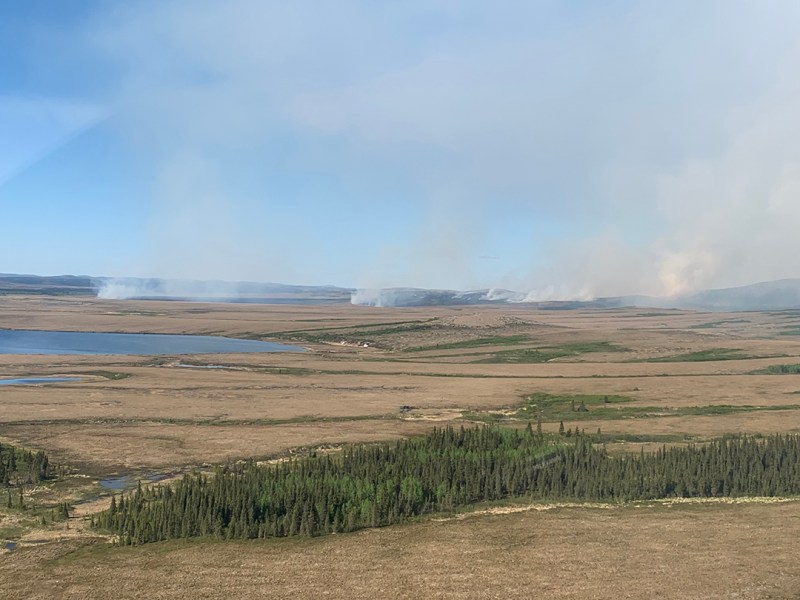 Photo of a flat tundra landscape with wispy smoke columns.