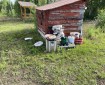 A picture of fire hoses stacked in front of a red shed. Showing grass and trees in the background.