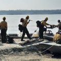 This photo shows crew members from a Hot Shot crew loading themselves and their equipment into seeveral boats on the banks of the broad Tanana River at Manley Hot Springs