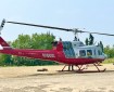 A red & white helicopter sits at the helibase and ready to transport personnel to the fire line.