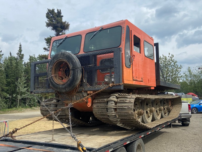 An orange piece of two-tracked heavy equipment sitting on a trailer.