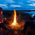 Four people sitting around a campfire shortly after sunset.