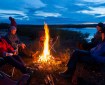 Four people sitting around a campfire shortly after sunset.