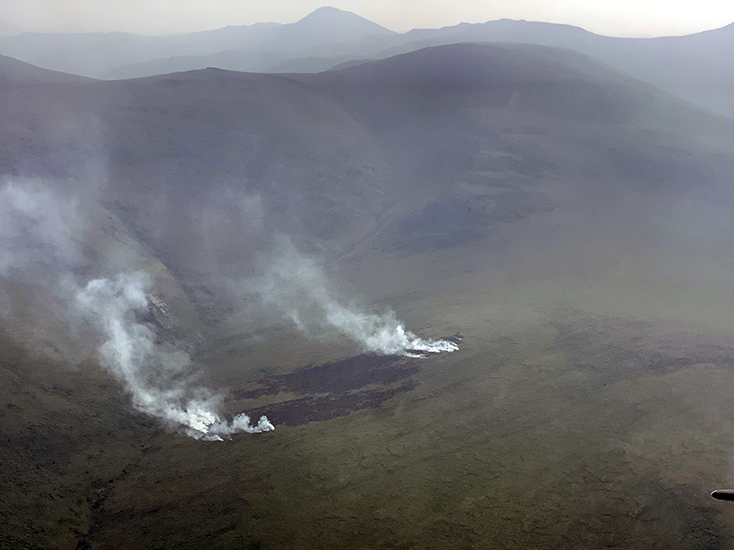 A blackened patch of ground with smoke rising.