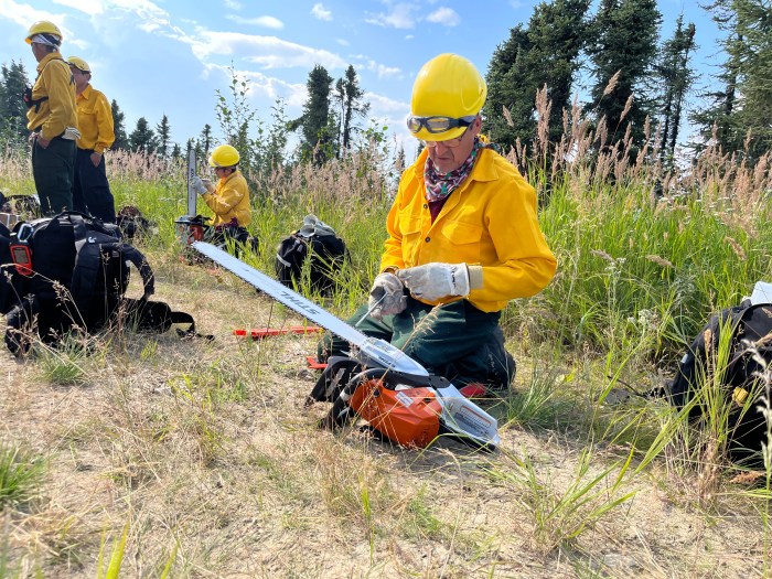 A firefighter sharpens his chainsaw.