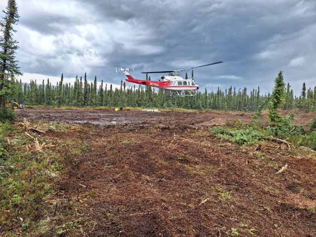 A helicopter lands on a fuel break.