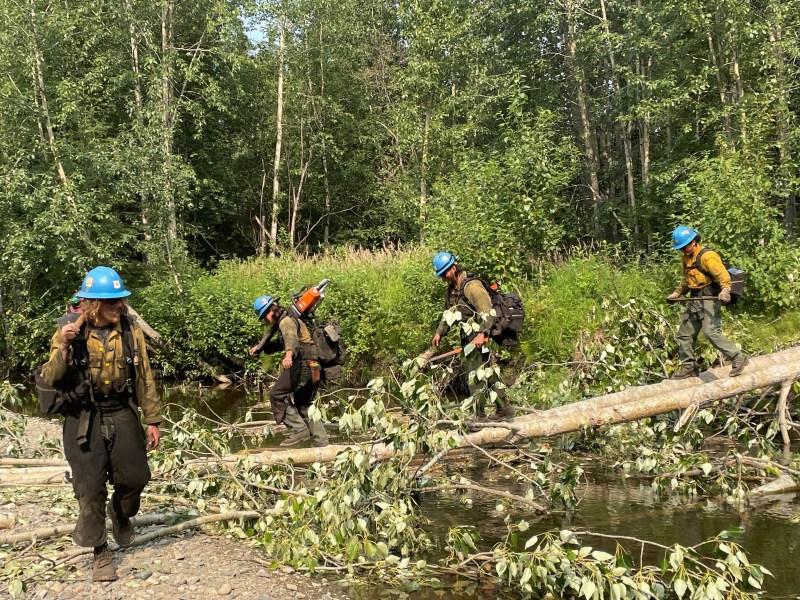 The Shasta Lake Hotshots cross a log bridge to reach a cabin near the Birch Creek Fire.