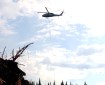 A Blackhawk helicopter flying away from the Teklanika River with an orange water bucket under a cloudy skye Shores Landing Fire (#325)