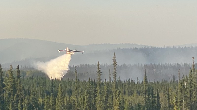 A super scooper drops water on a boreal forest in Alaska