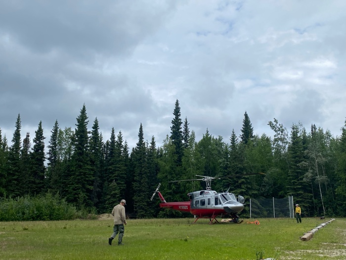 A person walks to a helicopter parked in a field.