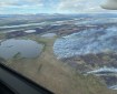 Aerial photo showing a large burned area with smoke drifting up from a tundra fire.