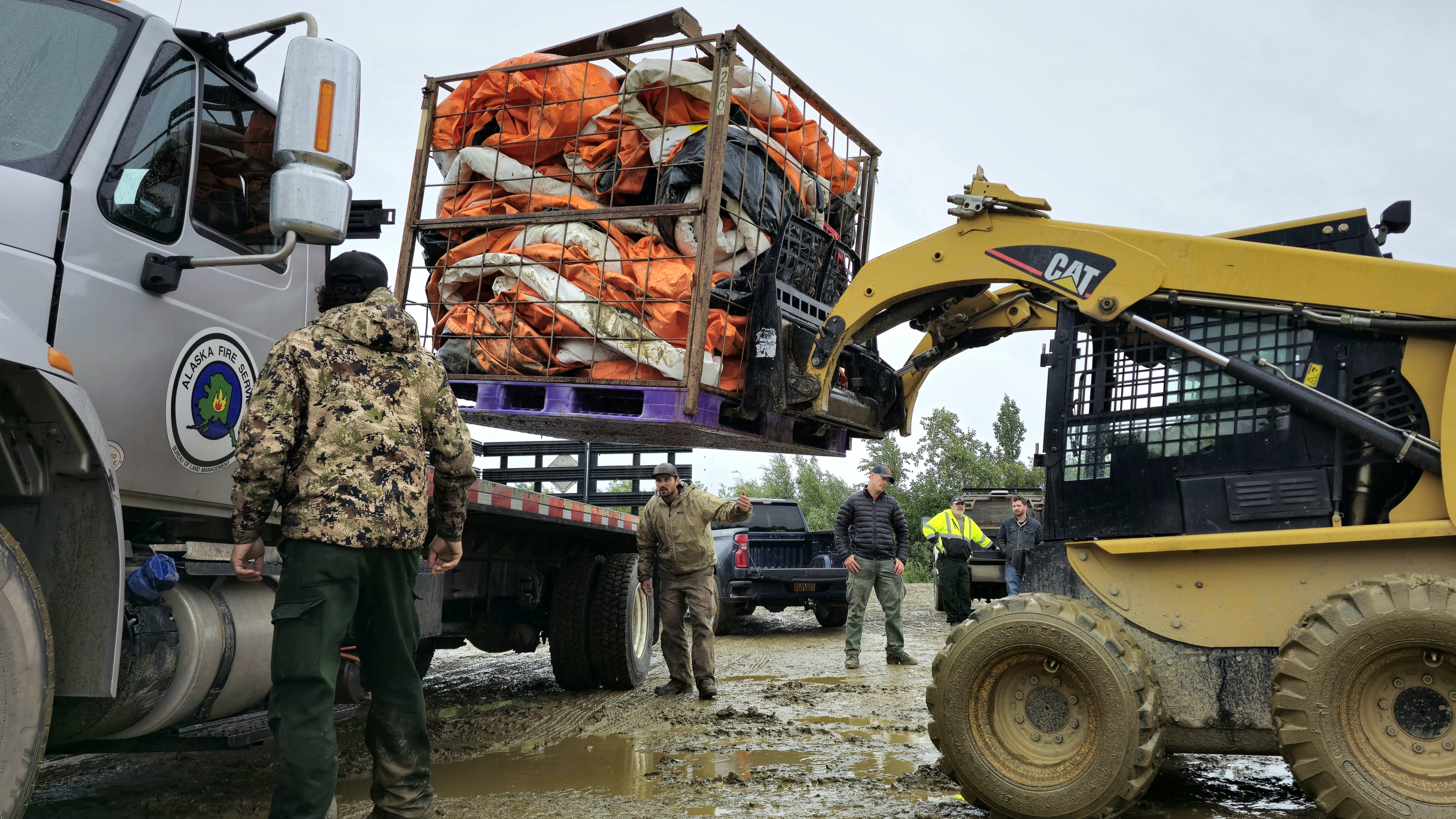 Skidster loads pallet of blivets on stake bed truck