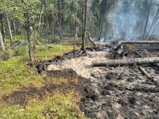A fire smolders in duff and timber