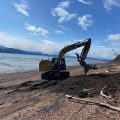 An excavator extinguishes a fire on a beach.