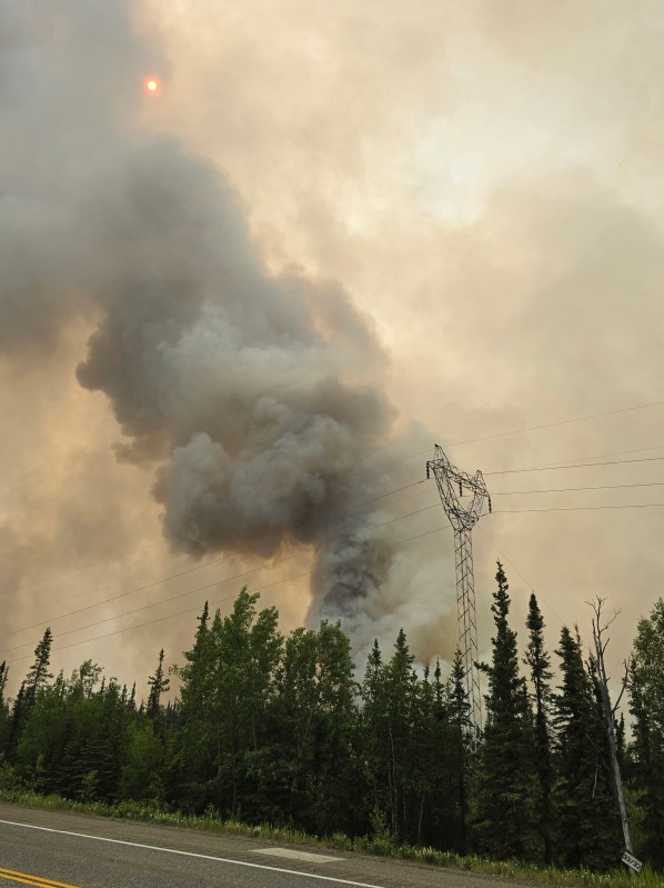 Smoke column with powerline, trees and road in the foreground. 