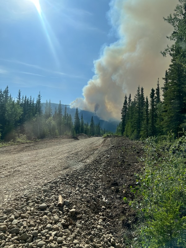 Image of a dirt road with a smoke column in the distance