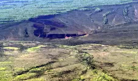 A black spot among a slope showing a burned area from a wildfire.