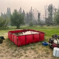 Folding tank holding water for firefighting operations, with hoses, pump, fuel and other equipment near by.