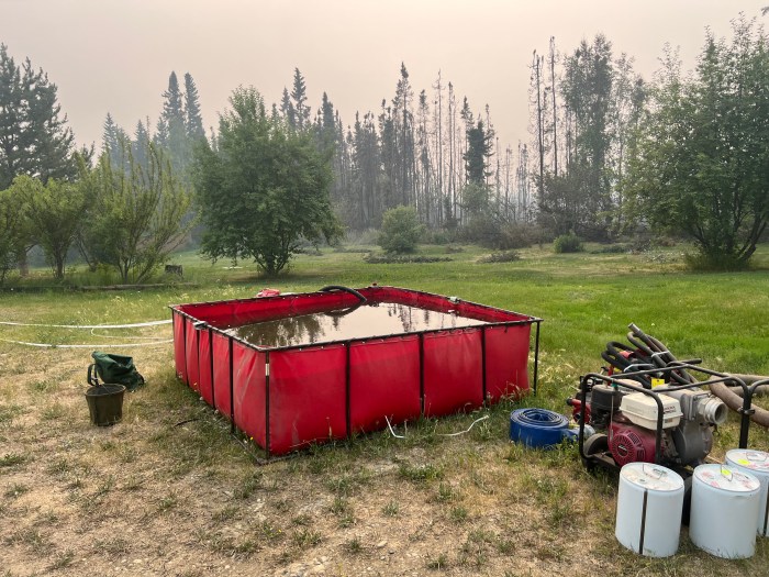 Folding tank holding water for firefighting operations, with hoses, pump, fuel and other equipment near by.
