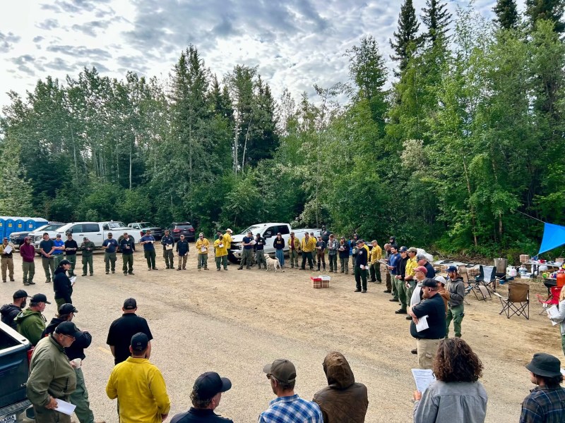 Photos shows firefighters gathered in a circle listening to morning briefing for the day's operations.