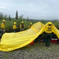 Fire crews use a yellow tarp to protect their gear from passing rain showers on the Nelchina Glacier