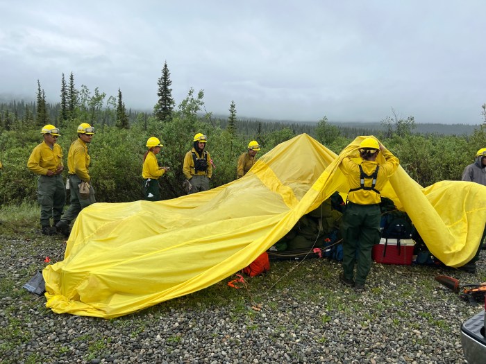 Fire crews use a yellow tarp to protect their gear from passing rain showers on the Nelchina Glacier