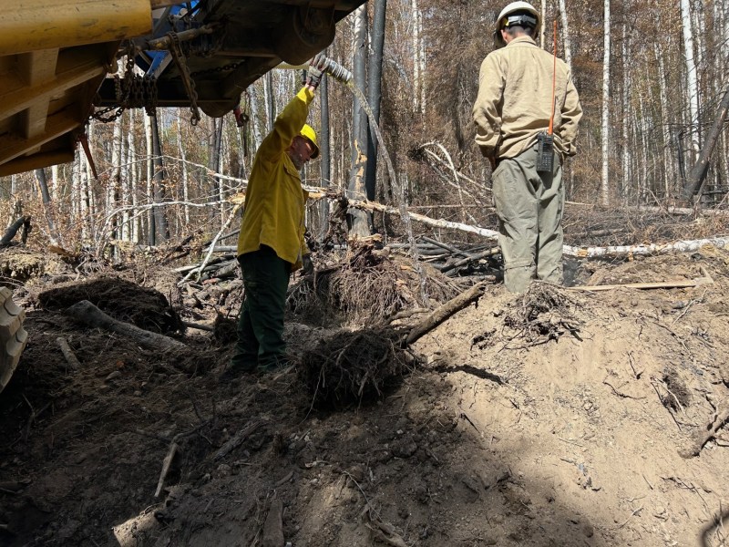 Heavy equipment and firefighters work to cool hot spots in berms.