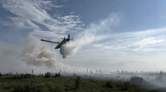 A single-engine scooper plane drops water on the fire.