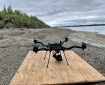 A drone sitting on a platform on the bank of a river.