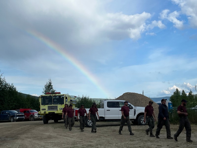 Rainbow over crew walking to dinner in camp.